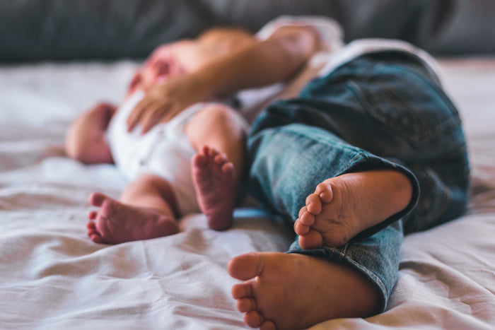 two sibling lie on bed baby toddler