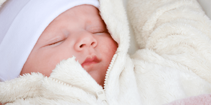 Baby looking forward, wearing a fluffy grey jacket with hood