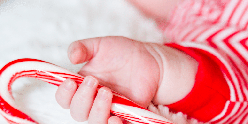 Baby wearing a santa hat, asleep on a white blanket